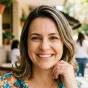 Mãe sorrindo para a câmera em uma varanda ensolarada.